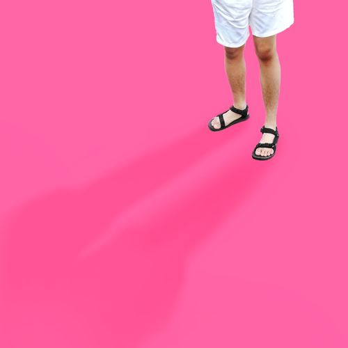 Low section of woman standing against pink background