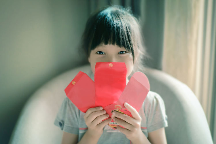 Close-up portrait of girl holding cards