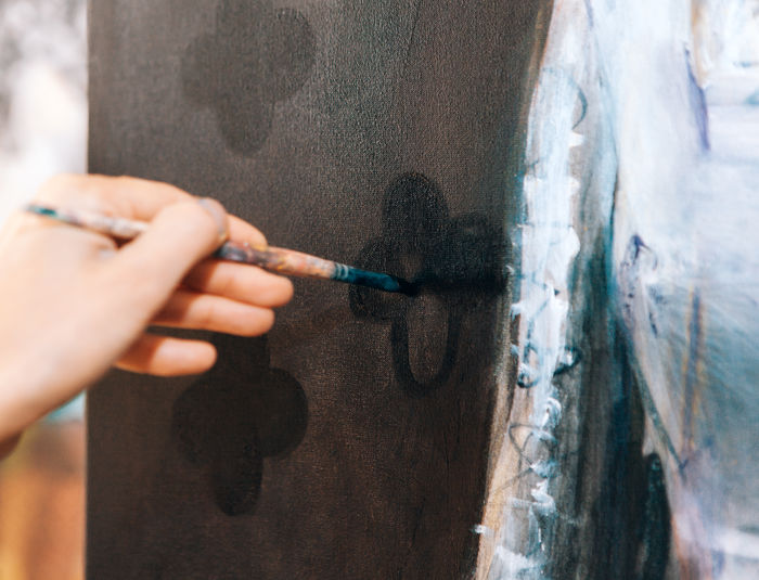 Close up on artist hand painting on canvas inside workshop studio