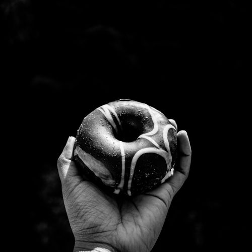 Cropped image of hand holding donut against wall