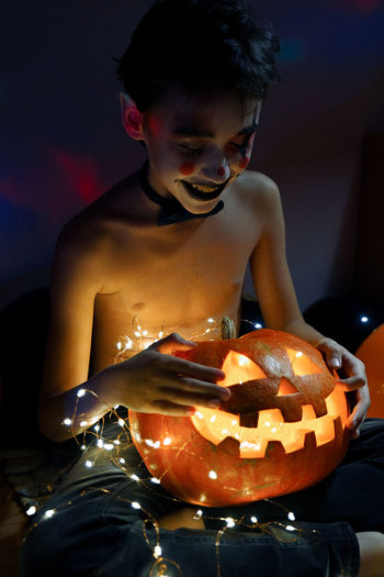 Full length of boy looking away while sitting on illuminated during halloween