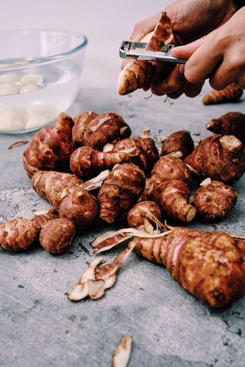 Cropped hands peeling jerusalem artichoke