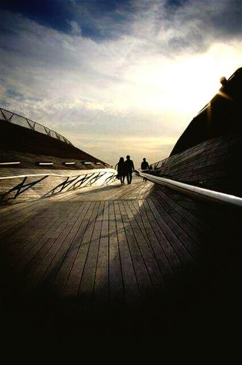 People walking on boardwalk at sunset