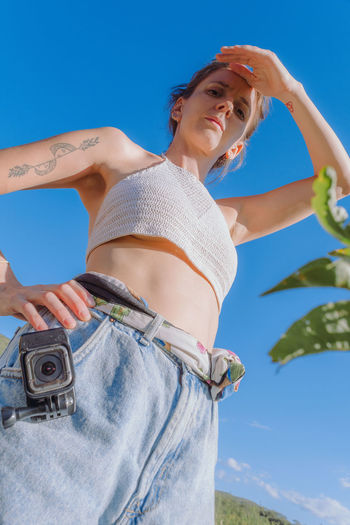 Midsection of woman standing against blue sky