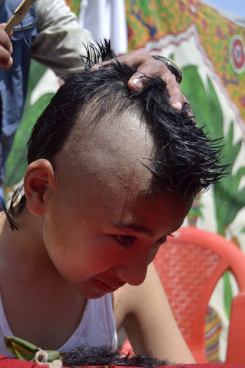Close-up of boy getting hair cut for bartaman ceremony
