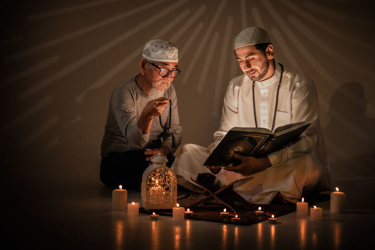 Two muslim people read and study islam holy al quran book together during ramadan period