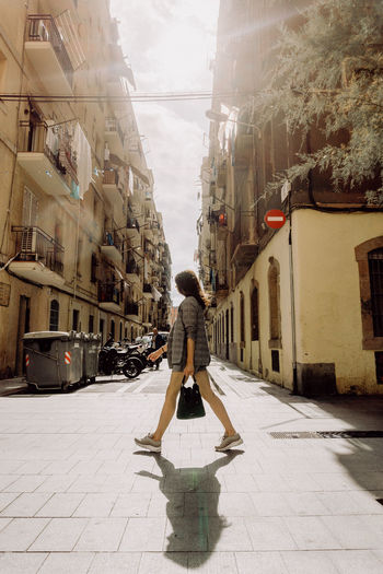 Rear view of woman walking on street amidst buildings