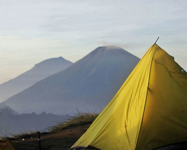 Yellow tent on mountain against sky