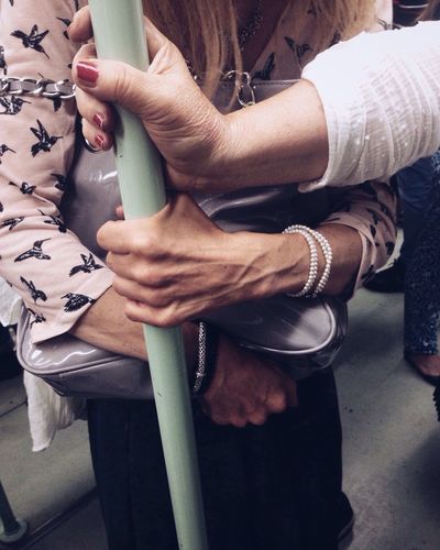 Midsection of women holding pole in train