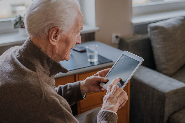 Close-up of senior man using digital tablet at home