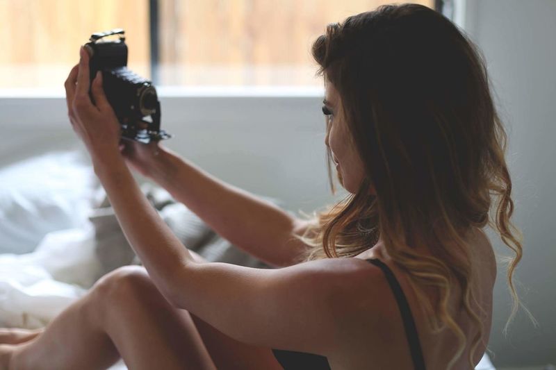 Woman taking selfie with analog camera