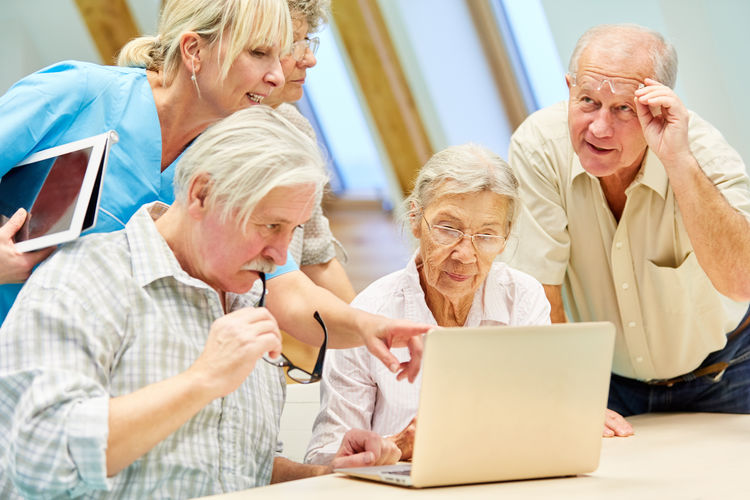 Nurse explaining something to senior citizens on laptop at table