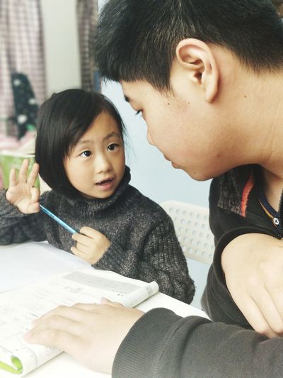 Teenage boy assisting sister in studying at home