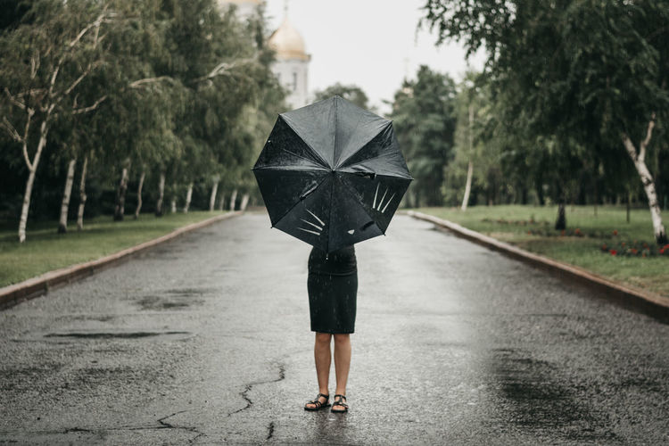 Full length of woman with umbrella standing on road
