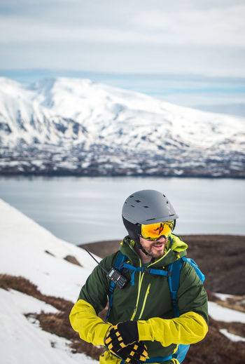 Man adjusting his glove skiing in iceland with water behind him
