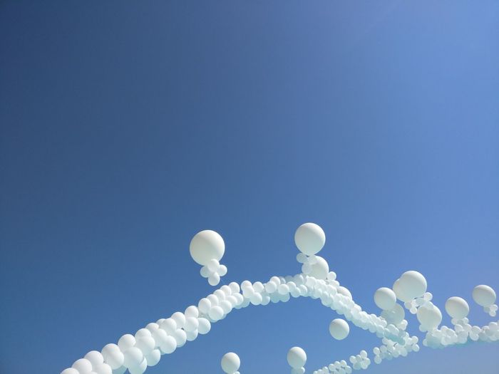 Low angle view of balloon decoration against clear blue sky