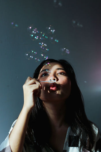 Portrait of a beautiful young woman looking at bubbles