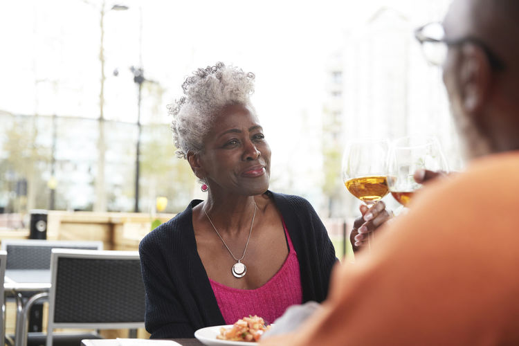 Smiling woman toasting drink with man at restaurant