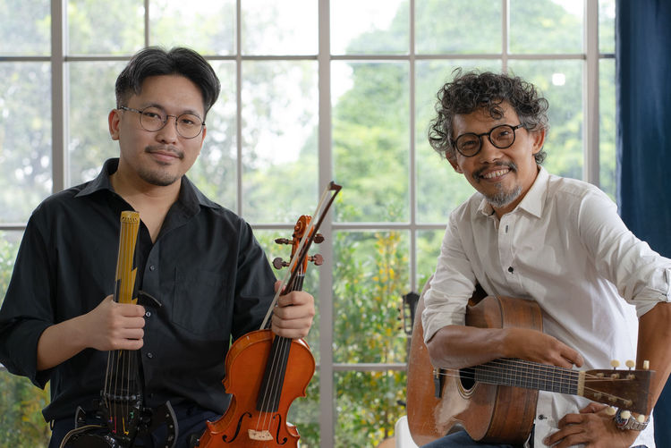 Portrait of two smiling asian musicians holding guitar and violin