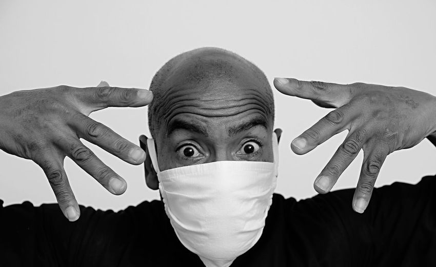 Portrait of man covering face against white background