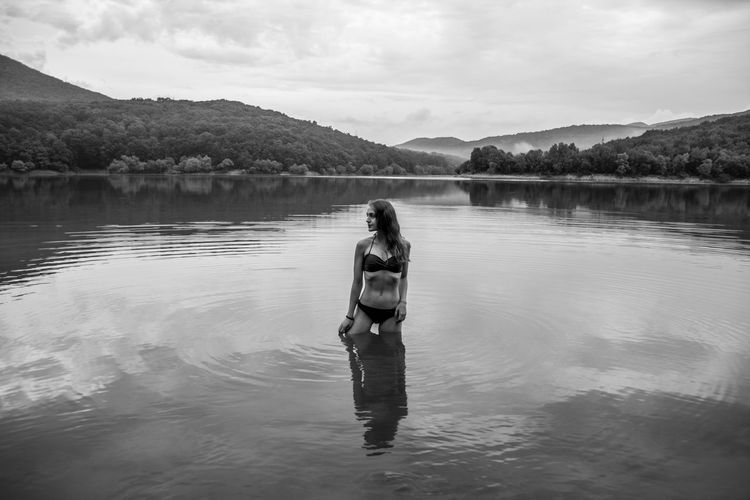 Woman standing in lake against sky