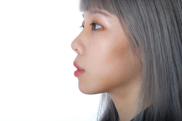 Close-up portrait of woman looking away against white background