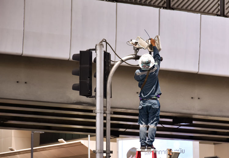 Worker set cctv camera on traffic pole.