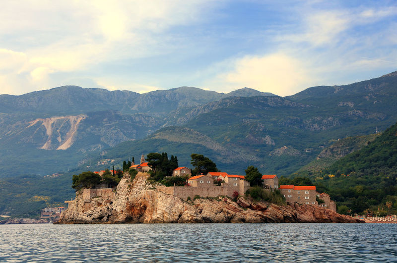 Sveti stefan by adriatic sea against mountains