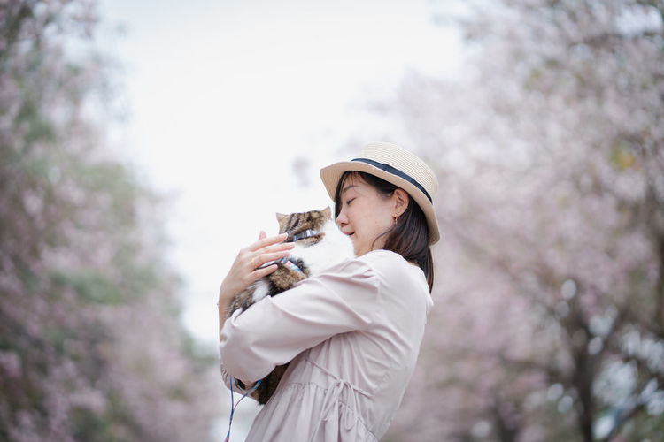 Asian woman travel outdoor with her cat with pink flower in springtime season
