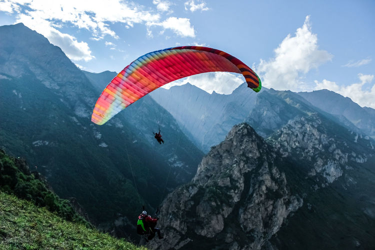 People paragliding on mountain peak against sky