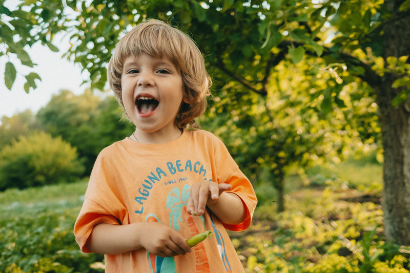 Portrait of happy boy holding green pea