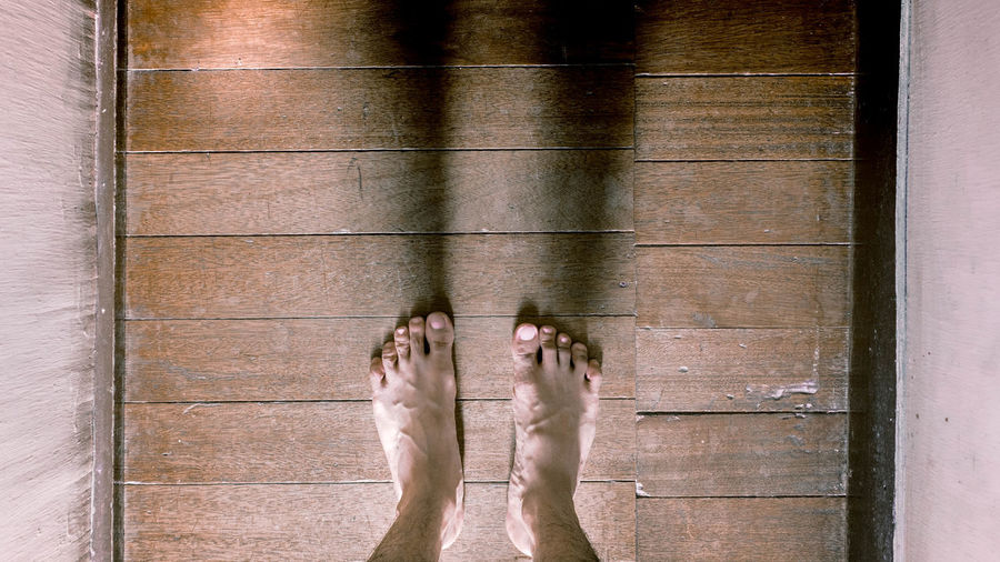 Low section of person standing on wooden floor