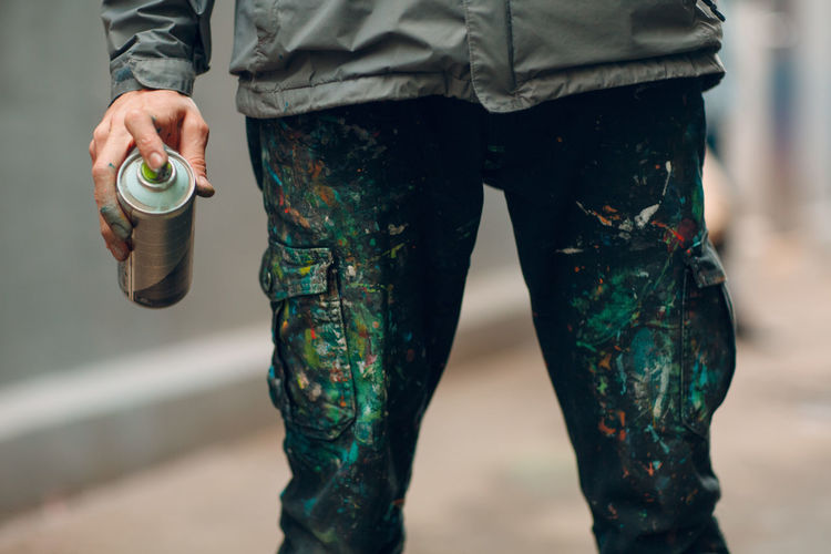 Midsection of man holding aerosol can outdoors