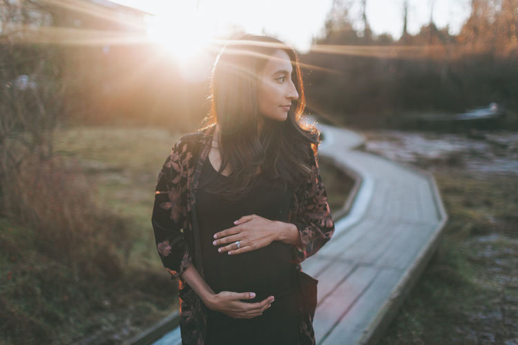 Pregnant woman standing at park during sunset