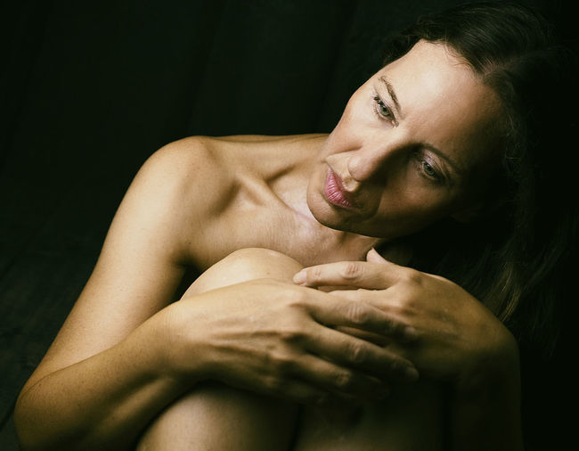 Close-up of shirtless young woman lying on bed
