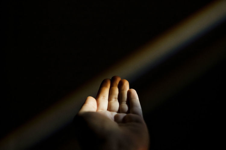 CLOSE-UP OF PERSON HAND AGAINST DARK BACKGROUND