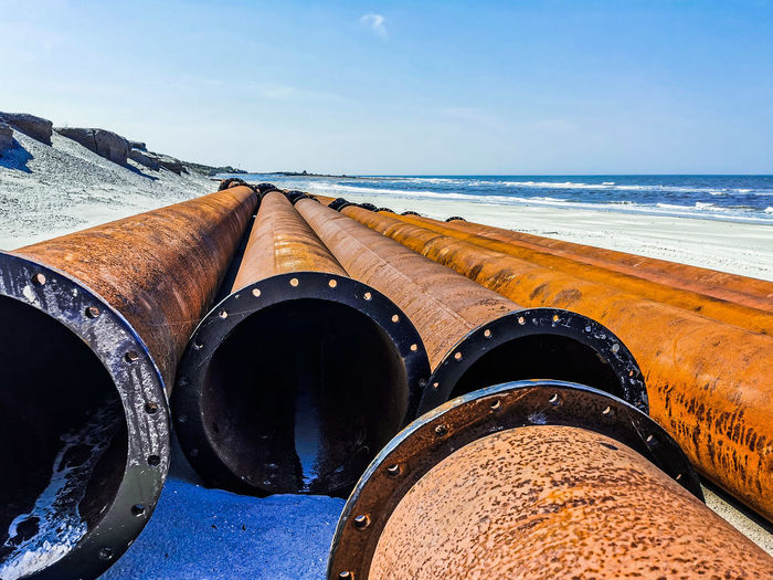 Close-up of rusty metal on beach against sky