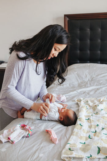 Mother wrapping toddler girl on bed at home