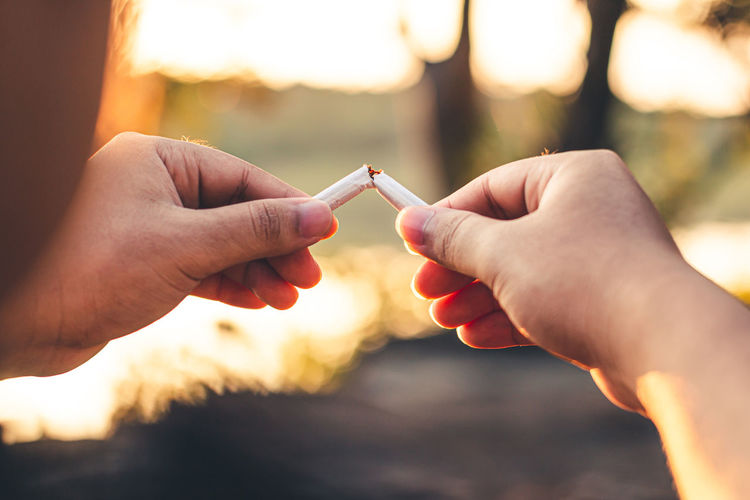 Men hand caught a burning cigarette causing smoke, concept stop smoking.