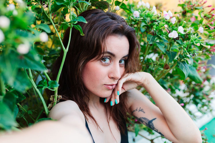 Portrait of young woman looking away against plants