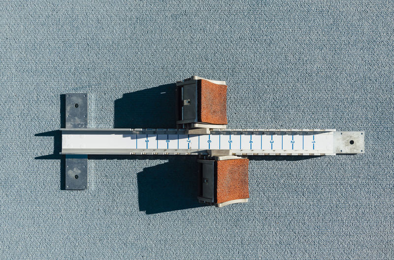 From above top view starting blocks placed on blue racetrack during track and field training on sunny day on stadium