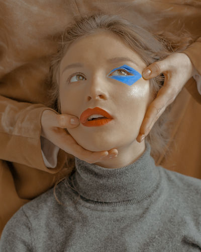 Cropped hands of person holding woman make-up face
