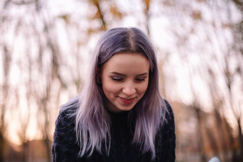 Portrait of cute smiling hipster young woman in park during autumn