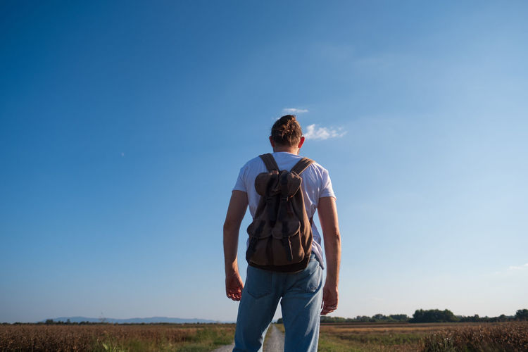 Rear view of man standing on land against sky