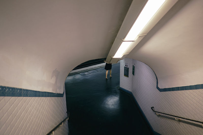 Low section of woman walking in illuminated subway station