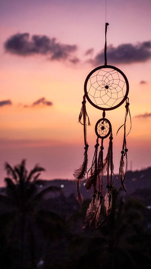 Close-up of silhouette decoration hanging against sky at sunset