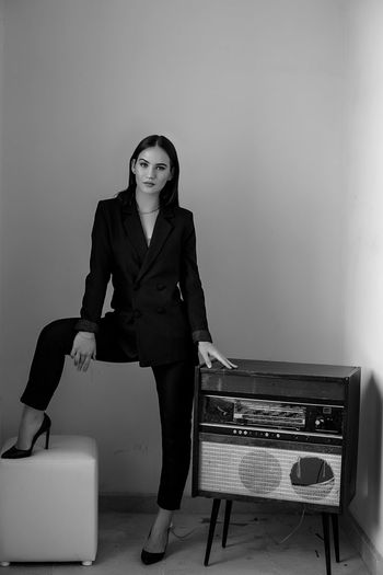 Portrait of woman standing by vintage record player against wall