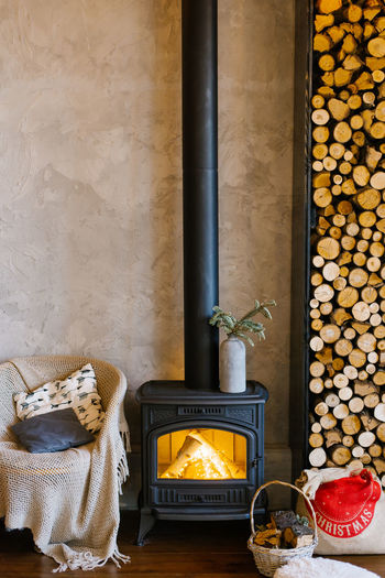 Retro fireplace, wood and armchair with a blanket and pillows in a country house
