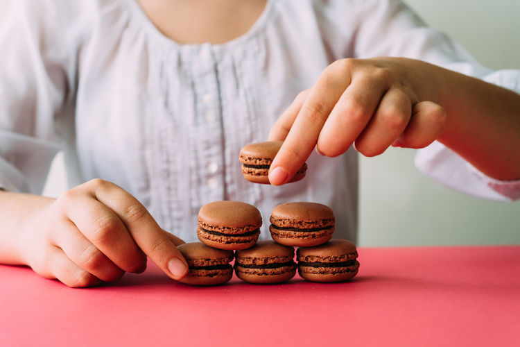 Midsection of woman arranging macaroons on table