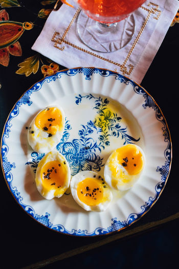 Top down shot of soft boiled eggs on plate with cocktail to the side